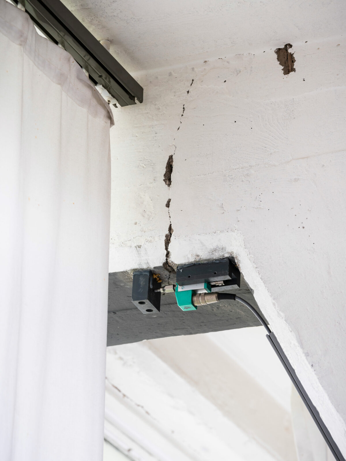 An einem Unterzug im WErkstattflügel des Bauhausgebäudes ist ein Messgerät montiert, dass die Schwingen der Fassade aufzeichnet. Detailansicht