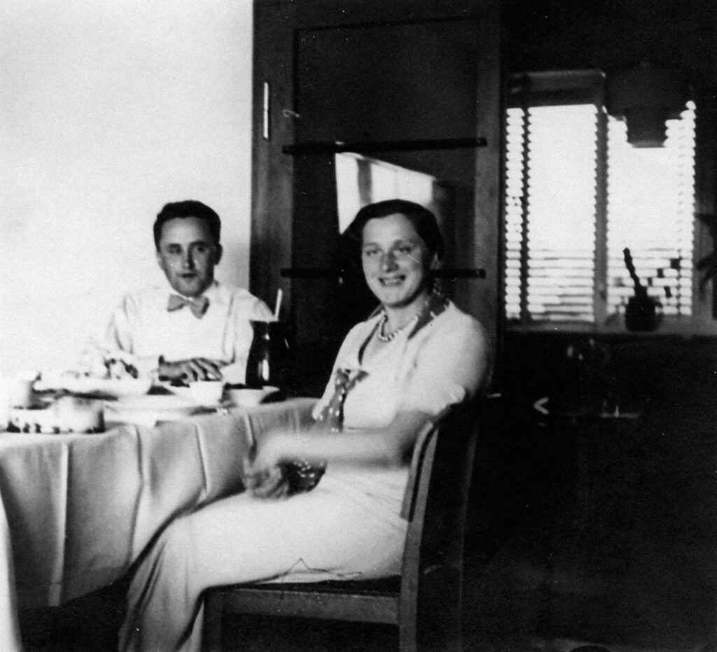 Friedrich Engeman und seine Frau sitzen am Esstisch. Sie lächelt und er schaut sie bewundernd an.